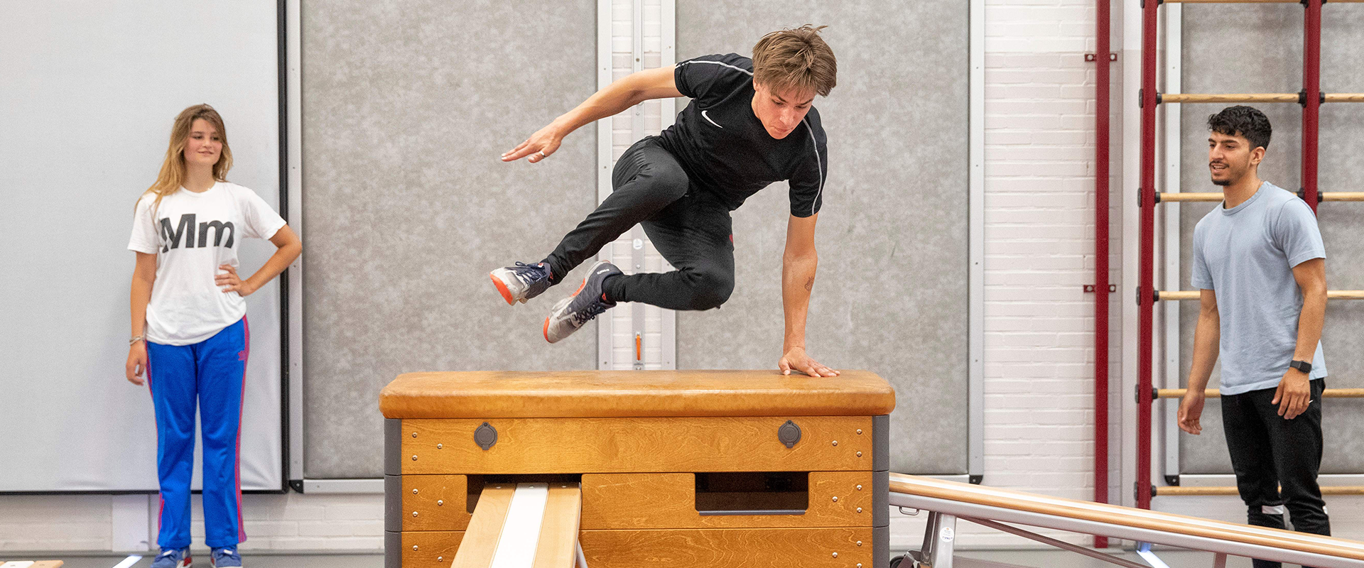 Jens springt over een kast in de gymzaal tijdens een training van freerunners rooftop kings